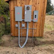Outdoor electrical meter and enclosures mounted on a wood backboard